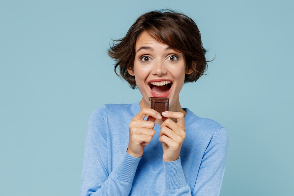 cute girl eating chocolates because her healthy diet and oral hygiene