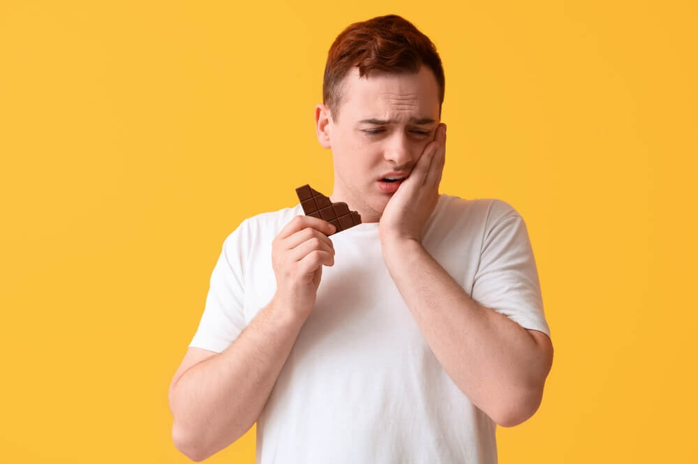 Young man feeling teeth pain due to sensitivity due to chocolates