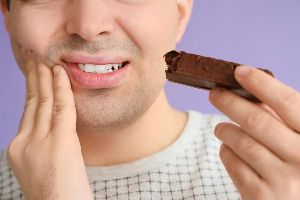 Young man hurts with tooth pain due to chocolate